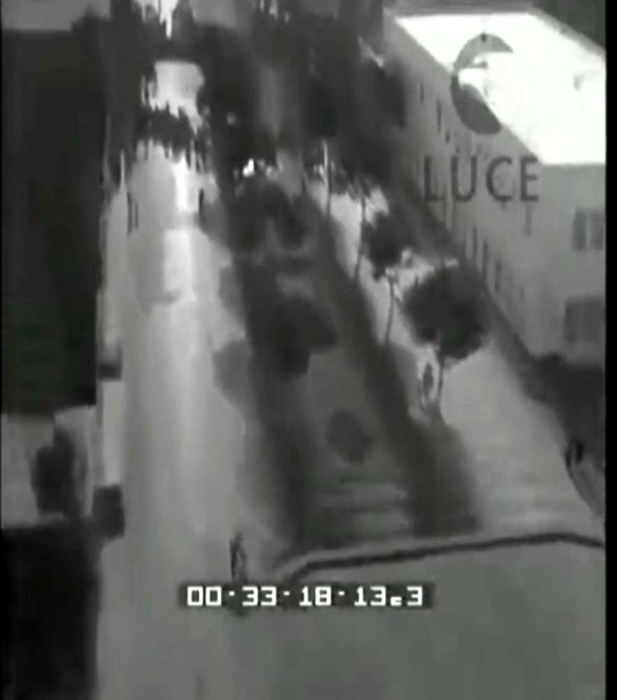 Vista aerea di una strada con un gruppo di persone e un edificio con la scritta 'LUCE'.